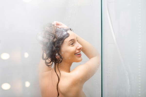 woman showering while laughing through shower window 